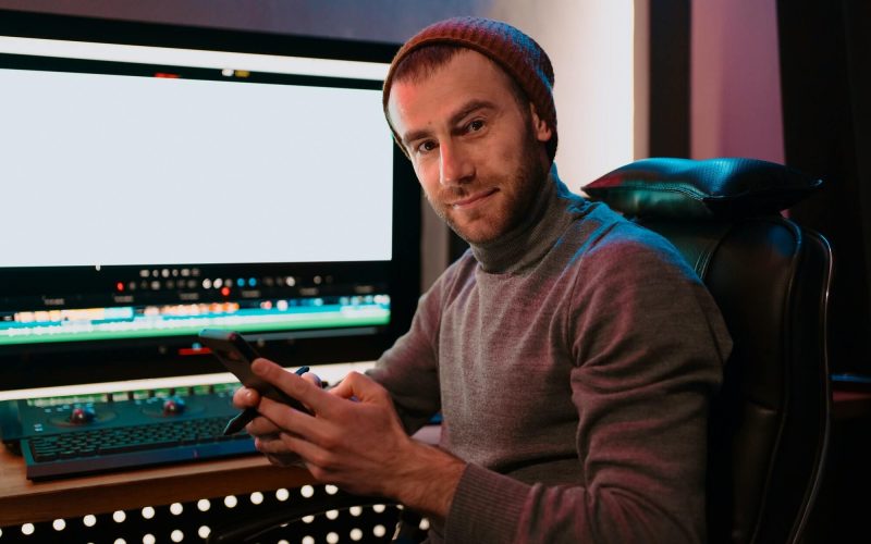male-video-editor-sitting-at-his-computer-using-phone-1.jpg